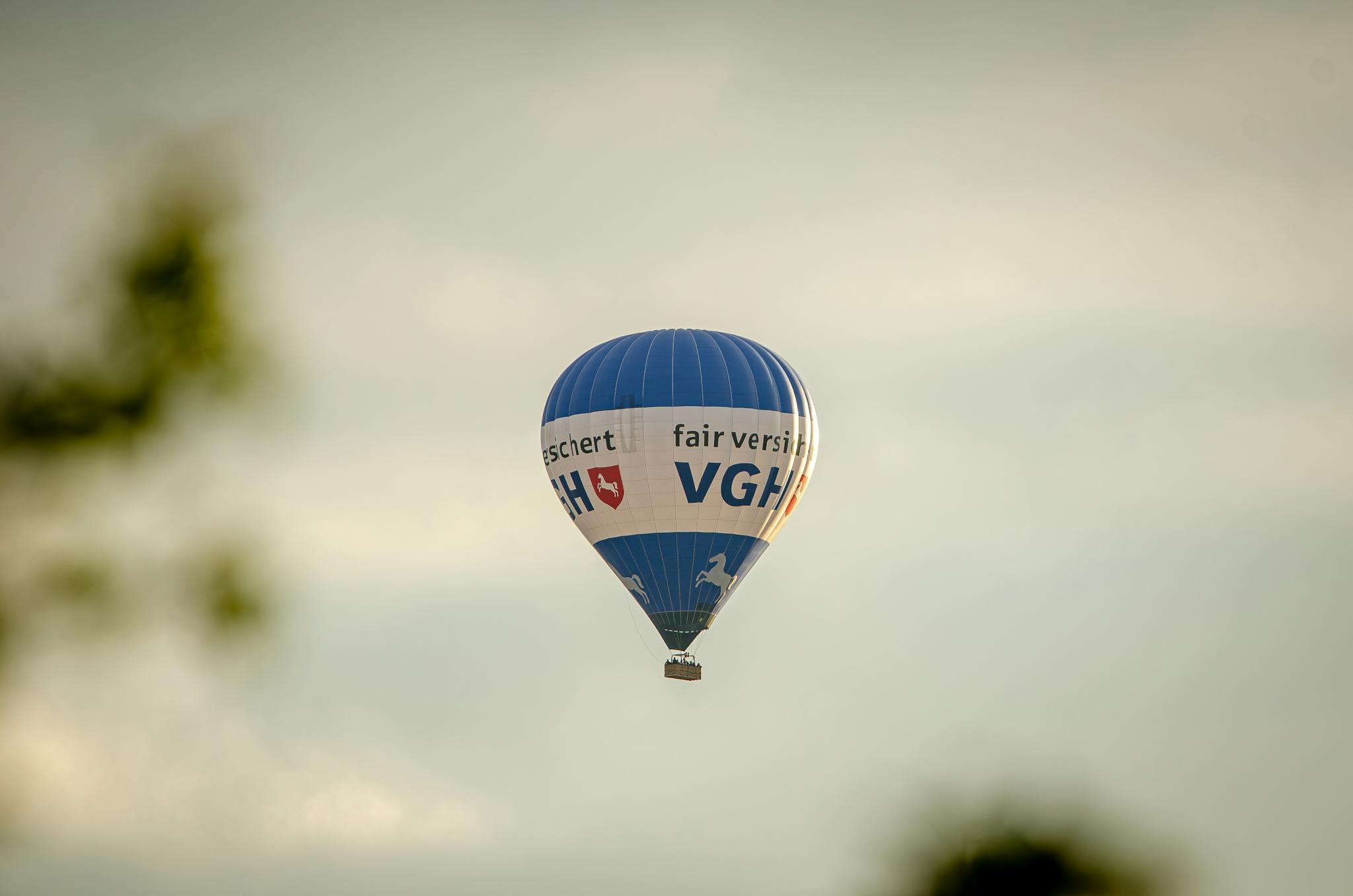 A blue hot air balloon with text flying in a clear sky, creating a serene travel scene.