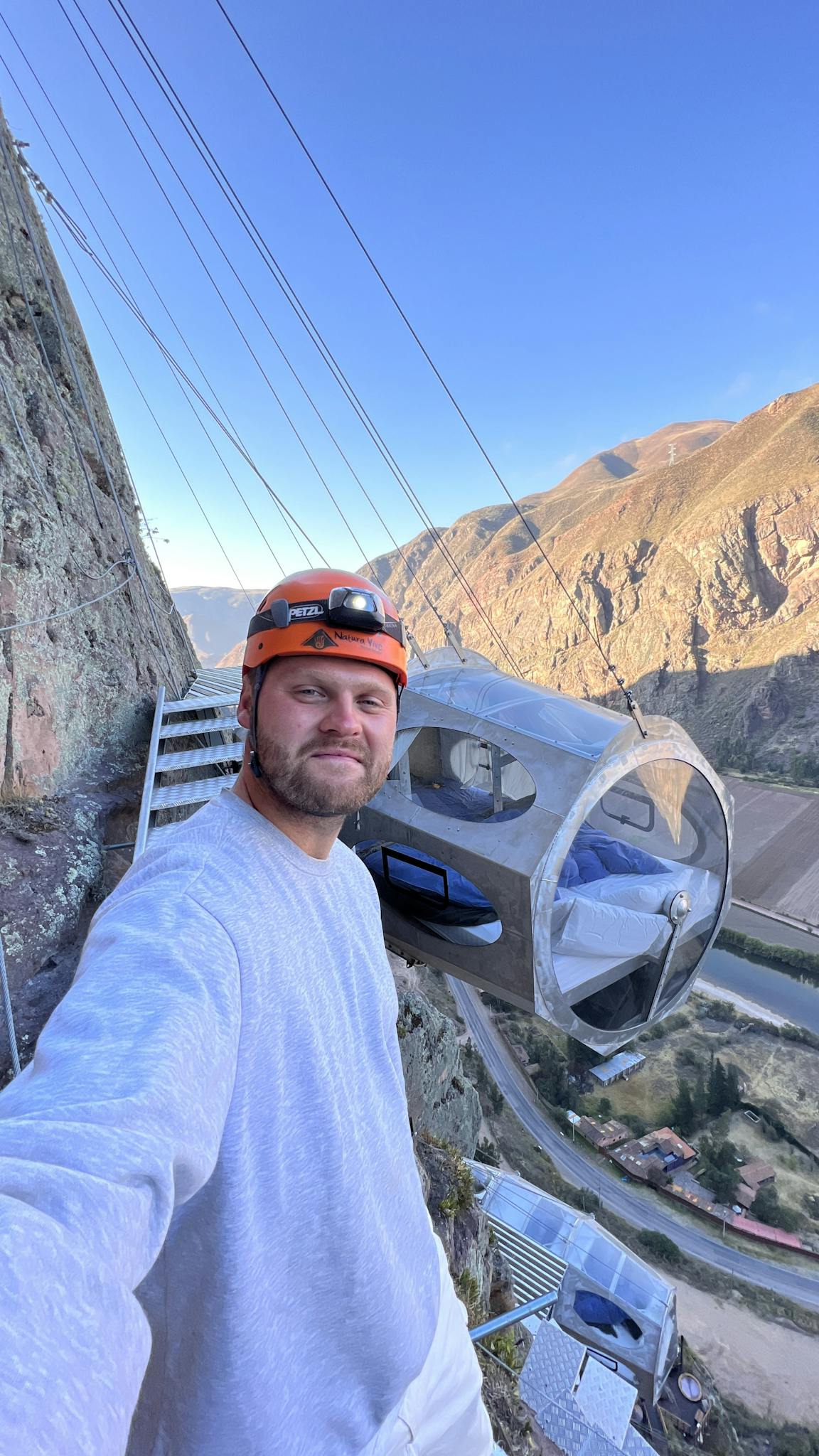 Man enjoying a thrilling stay in a cliffside pod overlooking Sacred Valley, Peru.